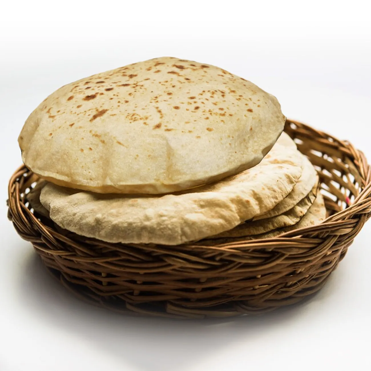 Freshly made soft chapatis stacked in a woven basket